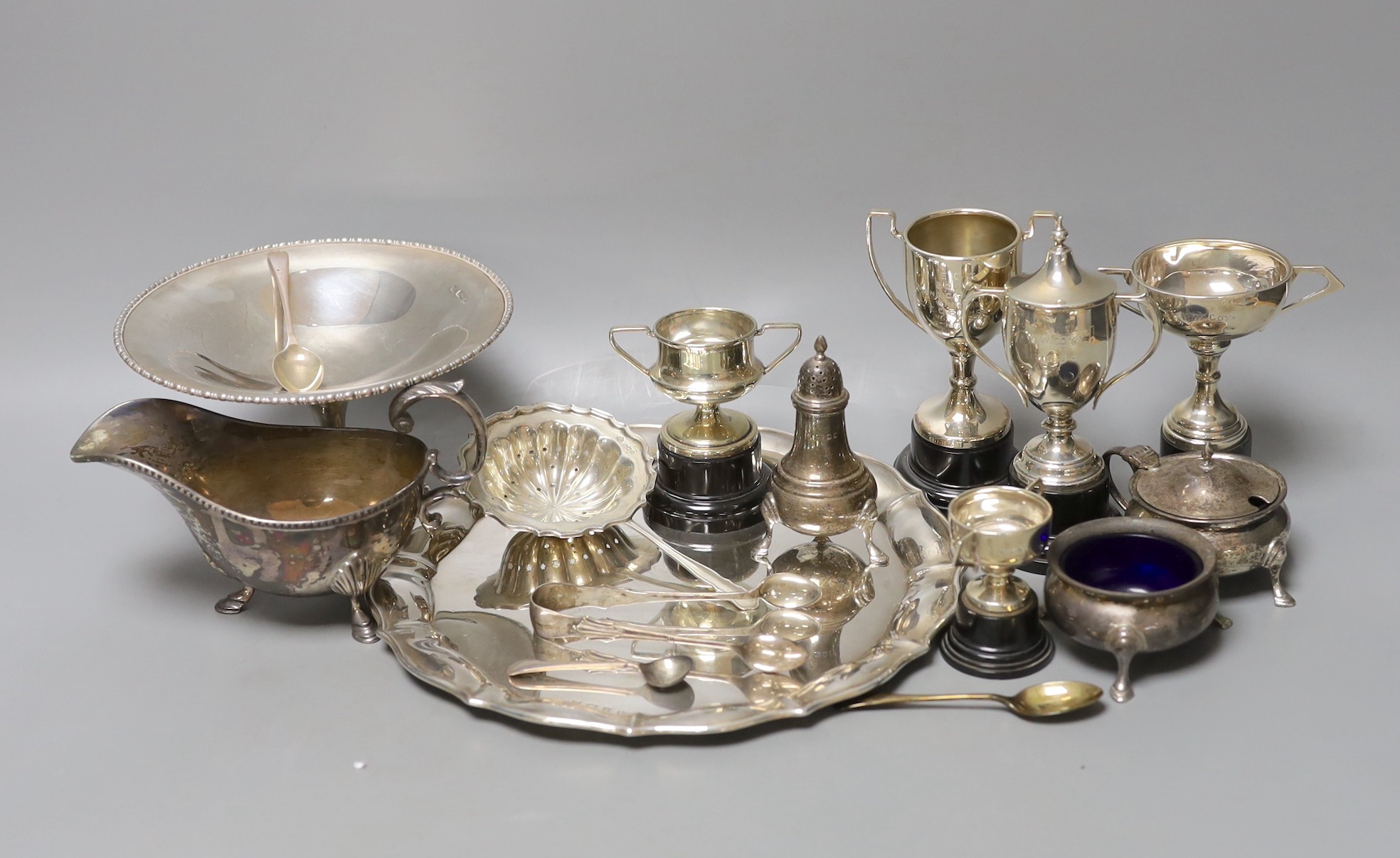 A George V silver salver, a silver tazze, a silver sauceboat, three silver condiments, a silver tea strainer, four items of silver flatware, three small silver trophy cups and two plated cups.